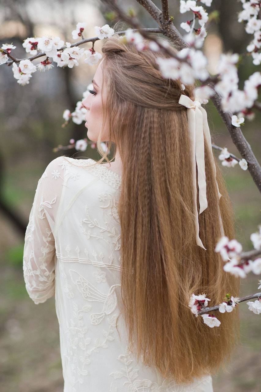 Bridal Half-up-Flechtfrisur mit Schleife zwischen Blütenzweigen