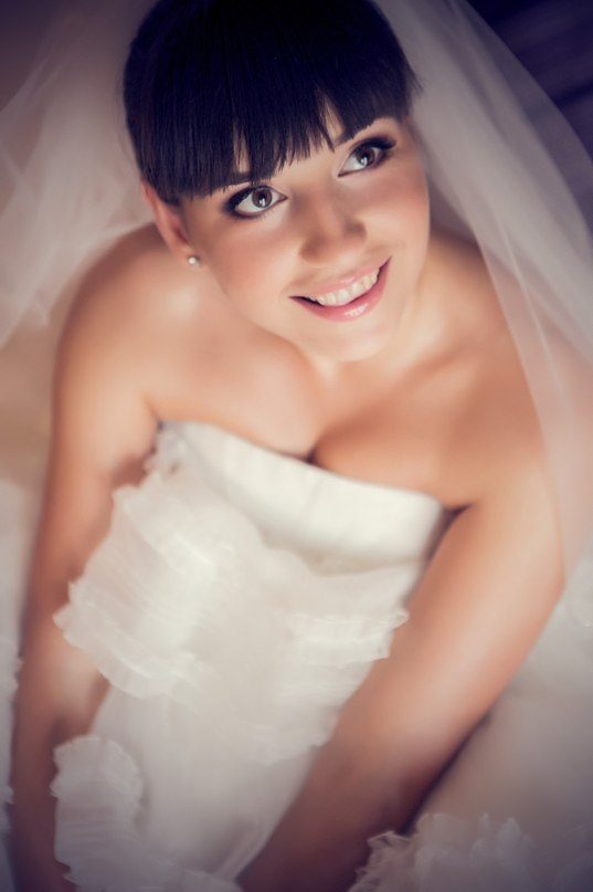 Mariée souriante avec frange et voile en robe bustier