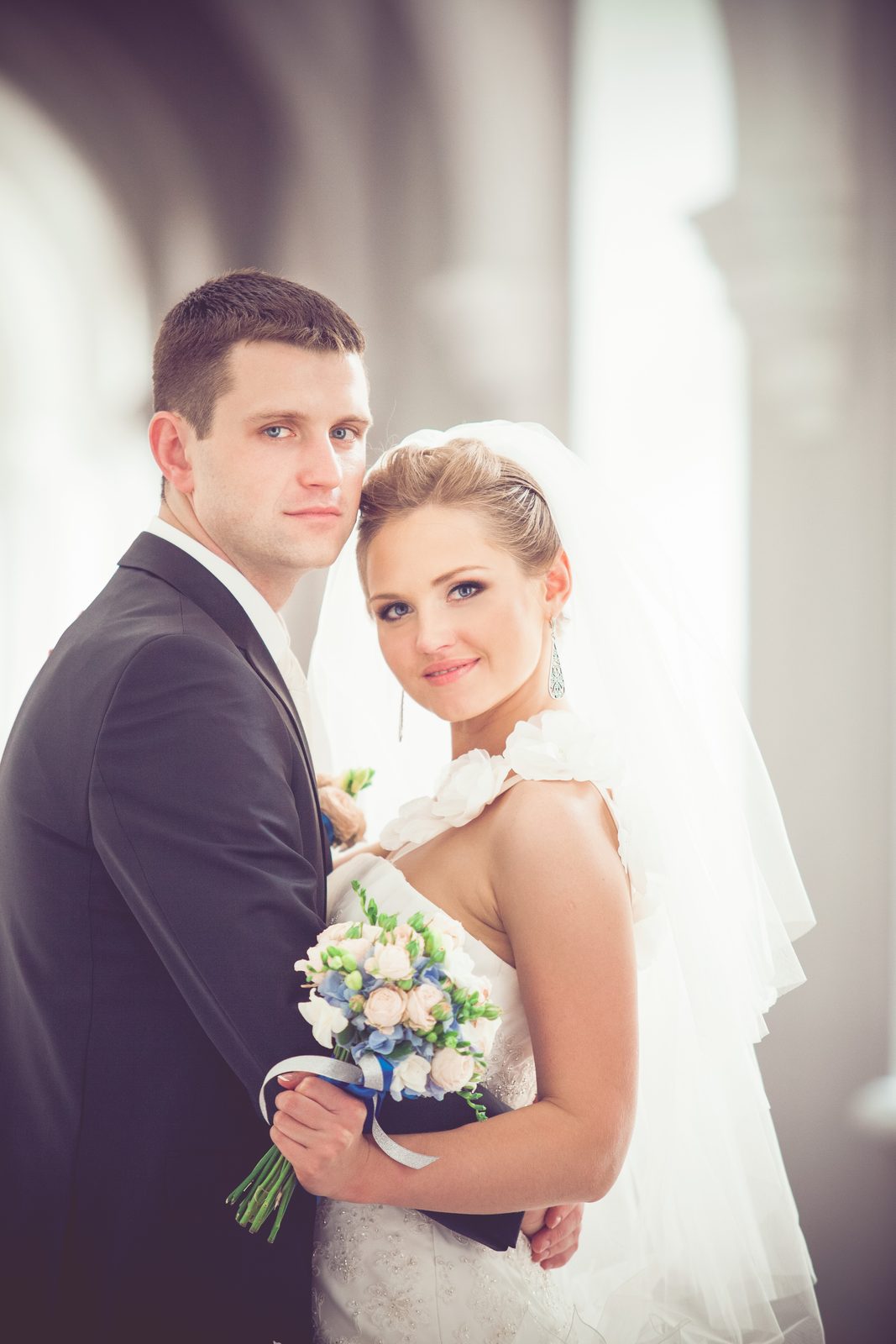 Portrait des mariés, la mariée voilée tenant un bouquet pastel