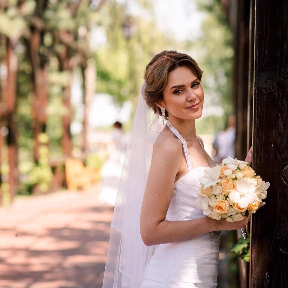 Mariée en robe dos nu et voile avec un bouquet pêche sur une terrasse ensoleillée