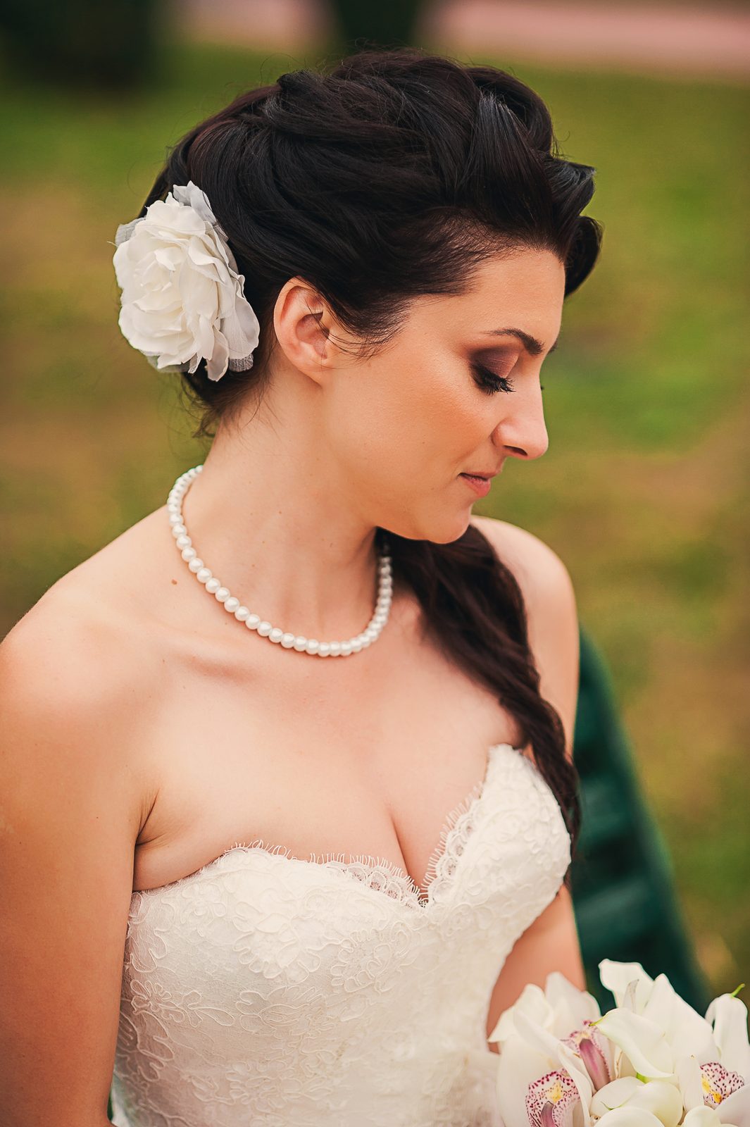 Sposa di profilo con acconciatura floreale e collana di perle