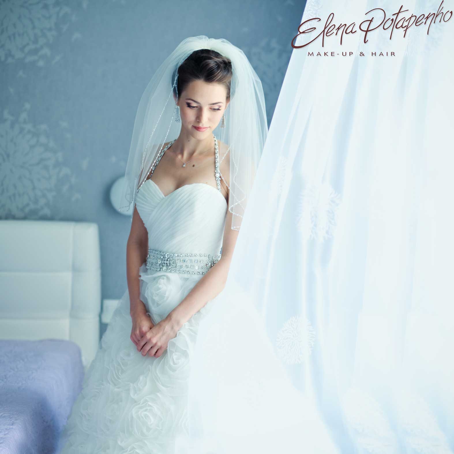 Mariée en robe bustier et voile dans une pièce bleu pâle