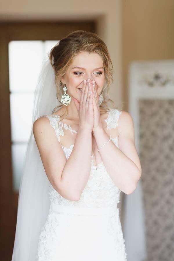 A bride in a veil, hands clasped, hair and makeup by Elena Potapenko in Veneto