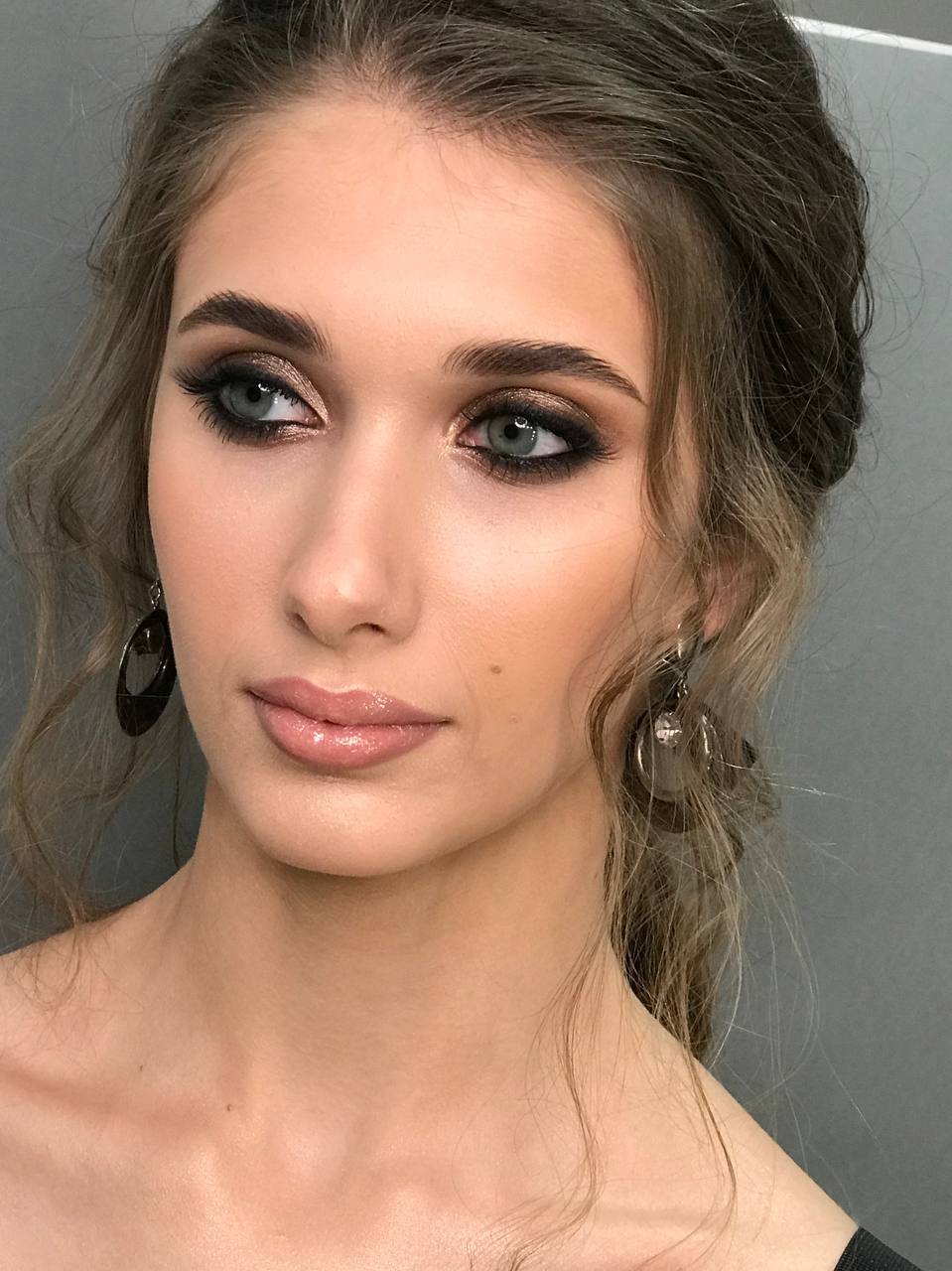 Bronzefarbenes Smokey Eye Make-up mit weichen Wellen und auffälligen Ohrringen
