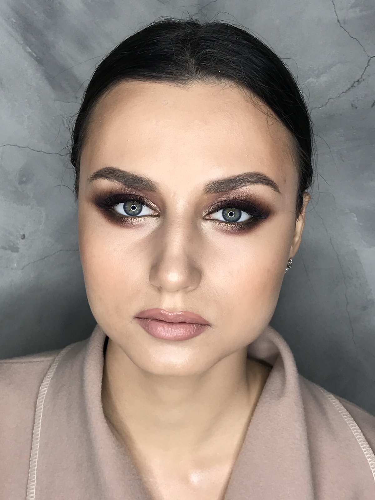 Brautmake-up-Porträt mit braunem Smokey Eye an einem brünetten Modell, zurückgekämmtes Haar