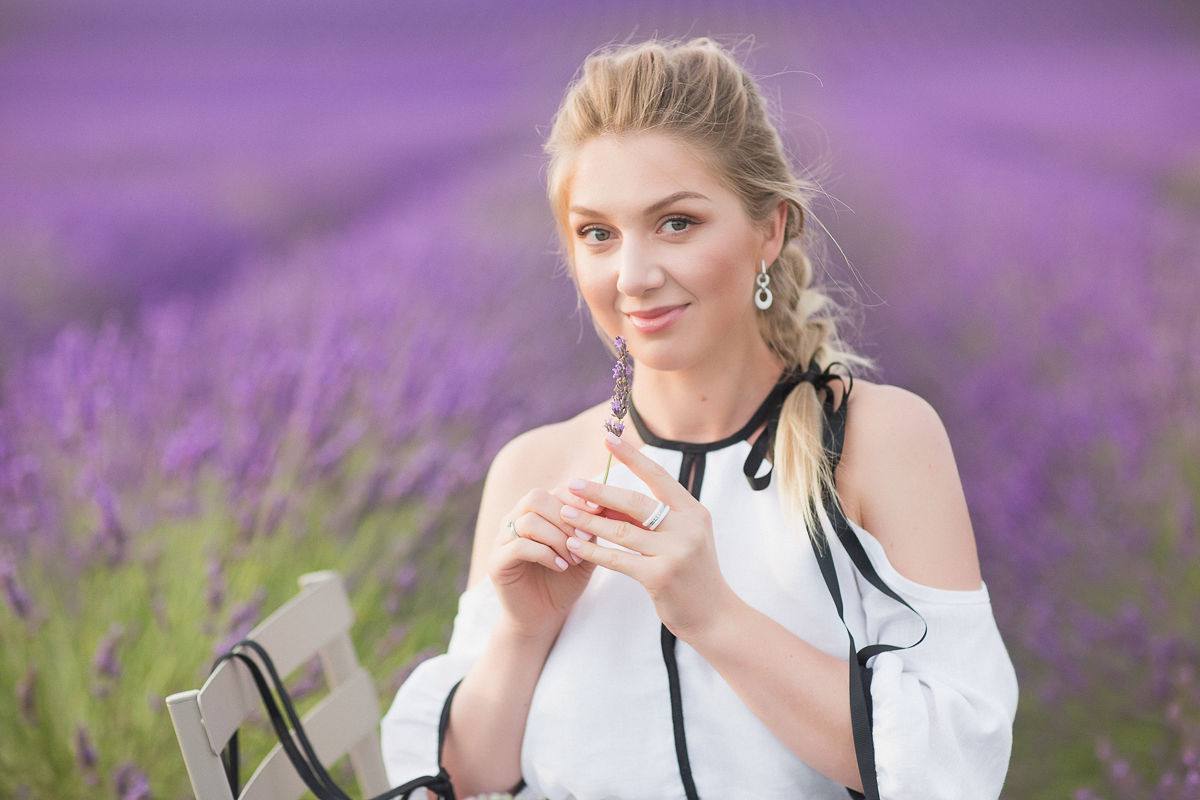 Glam-Make-up-Porträt in einem Lavendelfeld, ein Lavendelzweig in der Hand