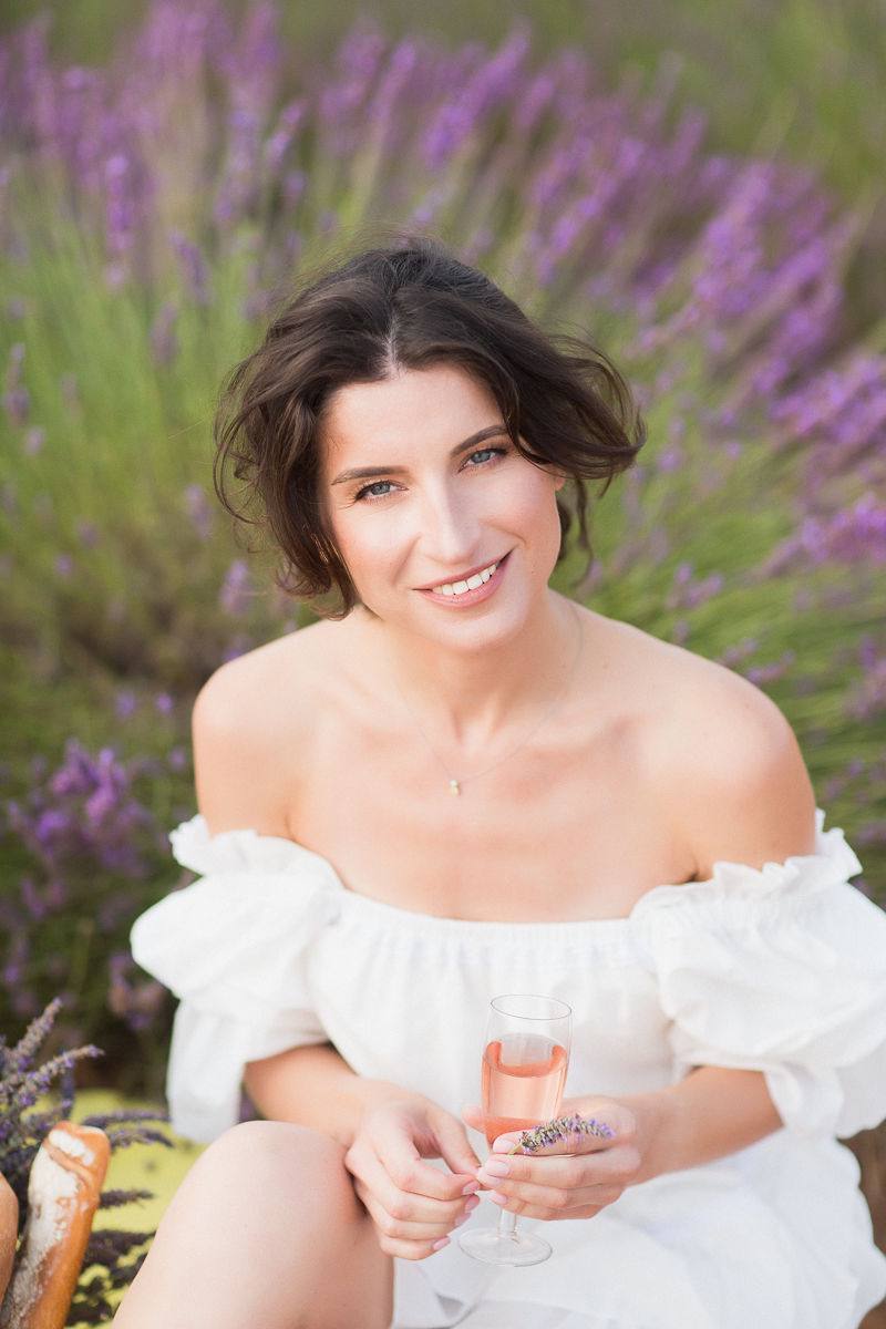 Glam-Make-up-Porträt in einem Lavendelfeld mit einem Glas Rosé
